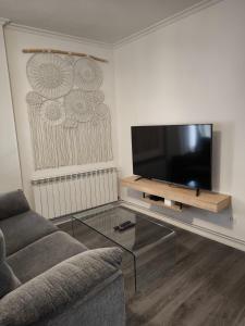 een woonkamer met een bank en een flatscreen-tv bij Apartamentos Crispin Anais in Corella