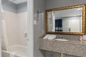 un bagno con un lavandino, uno specchio e una vasca di Golden Inn Dallas by Hotel O a Dallas Altre 67 foto