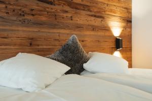 a bed with white pillows and a wooden wall at Hotel Matterhornblick in Zermatt