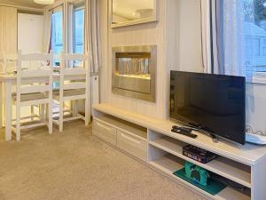 un soggiorno con TV a schermo piatto su un centro di intrattenimento di Dog Friendly 6 Berth Caravan With Decking Close To Pakefield Beach Ref 68067B a Pakefield