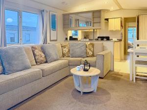 un soggiorno con un divano e un tavolo di Dog Friendly 6 Berth Caravan With Decking Close To Pakefield Beach Ref 68067B a Pakefield