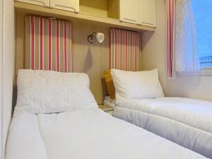 due letti uno accanto all'altro in una stanza di Dog Friendly 6 Berth Caravan With Decking Close To Pakefield Beach Ref 68067B a Pakefield Altre 11 foto