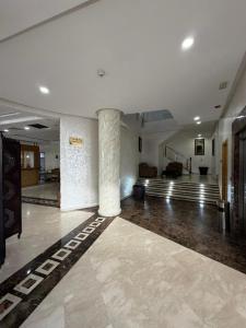 uma sala ampla com um hall de entrada com colunas e escadas em Hotel La Capitale em Rabat