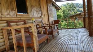 een veranda van een hut met stoelen en een raam bij Chanya homestay in Ban Yang