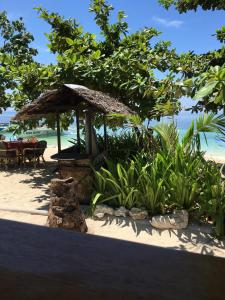 uma cabana na praia com mesas e cadeiras em Hippocampus Beach Resort em Malapascua Island