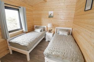 two beds in a room with wooden walls at Glenview Log Cabin in Ballycastle