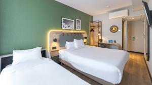 een slaapkamer met twee bedden en een groene muur bij Campanile PRIME - Lyon Centre - Gare Perrache in Lyon