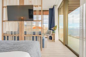 una camera da letto con un letto e una TV a parete di The Editory Ocean Way Funchal a Funchal