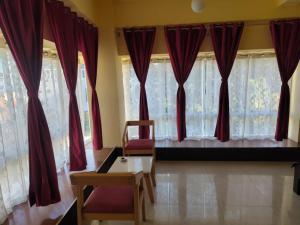 a room with red curtains and a chair and a table at D'Bonn Inn in Shillong
