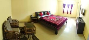 a bedroom with a bed and a chair and a television at D'Bonn Inn in Shillong