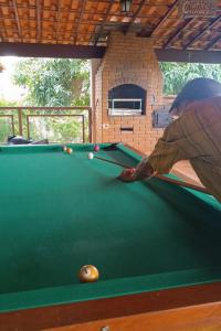 a man is playing pool on a pool table at Sítio flor do campo 7L in Sete Lagoas