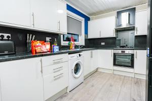 a kitchen with white cabinets and a washer and dryer at Mayfield House in Dalkeith