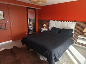 een slaapkamer met een groot bed met rode muren bij Cocon sensuel - Jaccuzzi et petit déjeuner - Proche Chantilly et Beauvais in Clermont