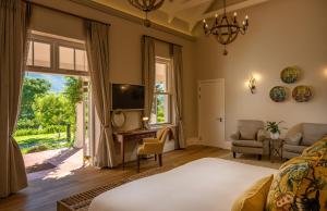 een slaapkamer met een bed, een tv en een raam bij Leeu Estates in Franschhoek