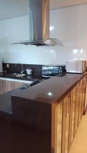 a kitchen with a black counter top with a microwave at Sítio flor do campo 7L in Sete Lagoas
