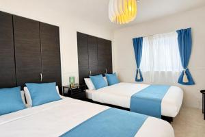 two beds in a room with blue and white at Sunstone Residence 2F - Free Rental Car & Airport Pickup - 10 Min to American Village in Ginowan