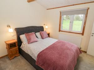 a bedroom with a bed with pink pillows and a window at Cedar Lodge in Rugeley