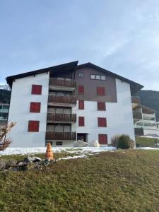 ein großes weißes Gebäude mit roten Fenstern auf einem Feld in der Unterkunft Satin Home in Savognin