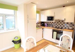 a kitchen with white cabinets and a table and chairs at 1 Bed in Bishopston oc-hh648 in Bishopston