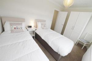 two white beds in a room with a chair at 3 Bed in Mumbles oc-hh668 in The Mumbles