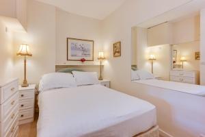 two beds in a white bedroom with two mirrors at 2 Bed in Gower oc-hh919 in Bishopston