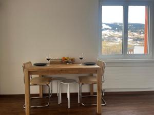 ein Holztisch mit Stühlen und Weingläsern in der Unterkunft Satin Home in Savognin