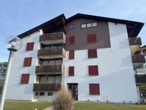 ein Wohnhaus mit roten Fensterläden und einer Straßenlaterne in der Unterkunft Satin Home in Savognin + 3 Fotos