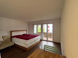 ein Schlafzimmer mit einem Bett, einem Stuhl und einem Fenster in der Unterkunft Satin Home in Savognin