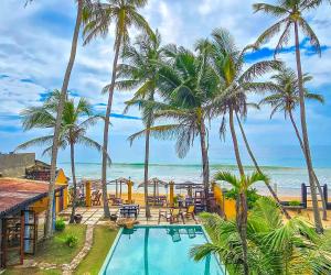 een resort met een zwembad en palmbomen en de oceaan bij Villa Kusum in Hikkaduwa