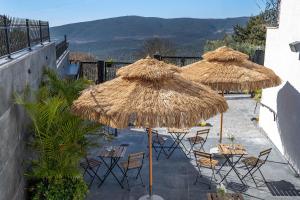 un patio con tavoli e sedie sotto ombrelloni di paglia di Cesia Boutique a Biriyya