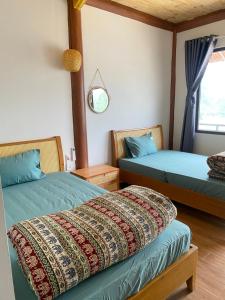 a bedroom with two beds and a window at Nhà Dâu Homestay in Muong Cha