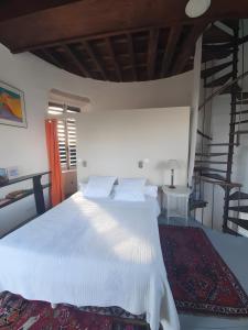 een slaapkamer met een wit bed en een trap bij Tour-Moulin in Épire