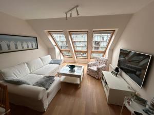 a living room with a white couch and some windows at Residence Rodin in Nieuwpoort