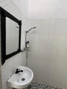 un bagno bianco con lavandino e specchio di Damar Tree Resort a Krui