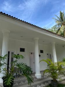 una casa bianca con colonne bianche e palme di Damar Tree Resort a Krui