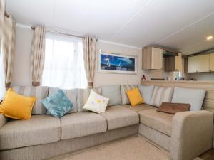 a living room with a couch with colorful pillows at Caravan number 77 in Eyemouth