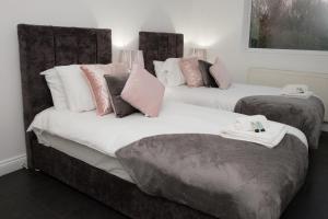 deux lits dans une chambre avec des oreillers roses et gris dans l'établissement K Suites - Fulbridge Road 116, à Paston