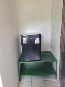un piccolo scaffale verde in una stanza con un microonde di Sítio Guanabara a Guaramiranga