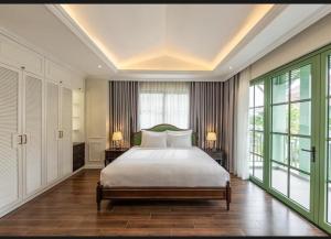 a bedroom with a large bed and large windows at Green Villas Tropical Phú Quốc in Phu Quoc
