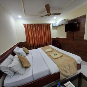 a bedroom with a large bed with white sheets at Hotel Tazzodisha Next in Bhubaneshwar +4 photos