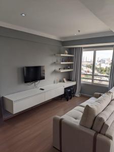 ein Wohnzimmer mit einem weißen Sofa und einem Flachbildfernseher in der Unterkunft GRU Airport Easy Stay in Guarulhos