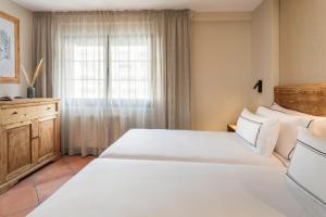 a bedroom with a large white bed and a window at Meliá Sol y Nieve in Sierra Nevada