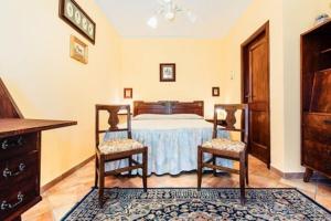 een slaapkamer met een bed en twee stoelen bij Agriturismo Lillastro Grosseto in Braccagni +30 foto's