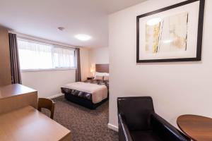 a small hotel room with a bed and a chair at Eastern Sands City Centre in Geelong