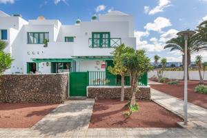 ein weißes Haus mit einem grünen Tor und Palmen in der Unterkunft Casa Real in Playa Blanca