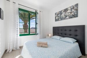 ein Schlafzimmer mit einem Bett mit blauer Bettdecke und einem Fenster in der Unterkunft Casa Real in Playa Blanca