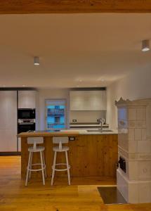 een keuken met een aanrecht en 2 krukken bij Casa Patty Moena in Moena +10 foto's