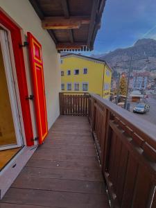 een houten balkon met een rode deur aan een gebouw bij Casa Patty Moena in Moena