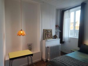 a bedroom with a bed and a table and a window at Le grenier à sel, maison de pécheur pour 6 avec salle TV in Fécamp