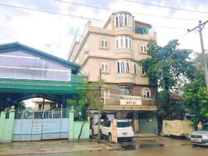 een gebouw met een wit busje ervoor geparkeerd bij Pandora Motel in Yangon